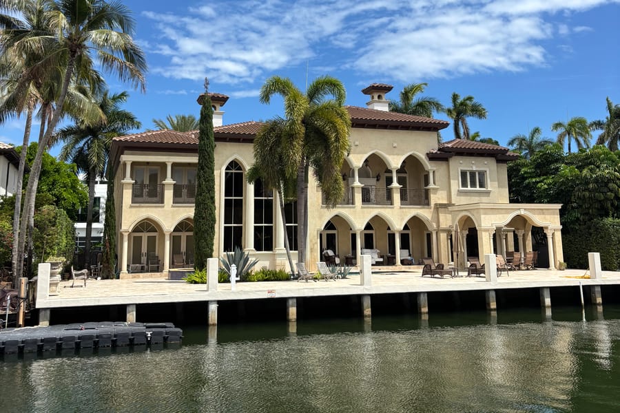 Large waterfront estate with palms along a South Florida canal