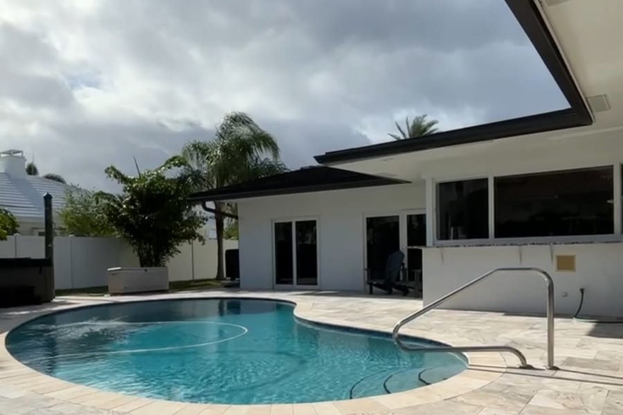 Pool and travertine deck behind a single storey home in Sea Ranch Lakes