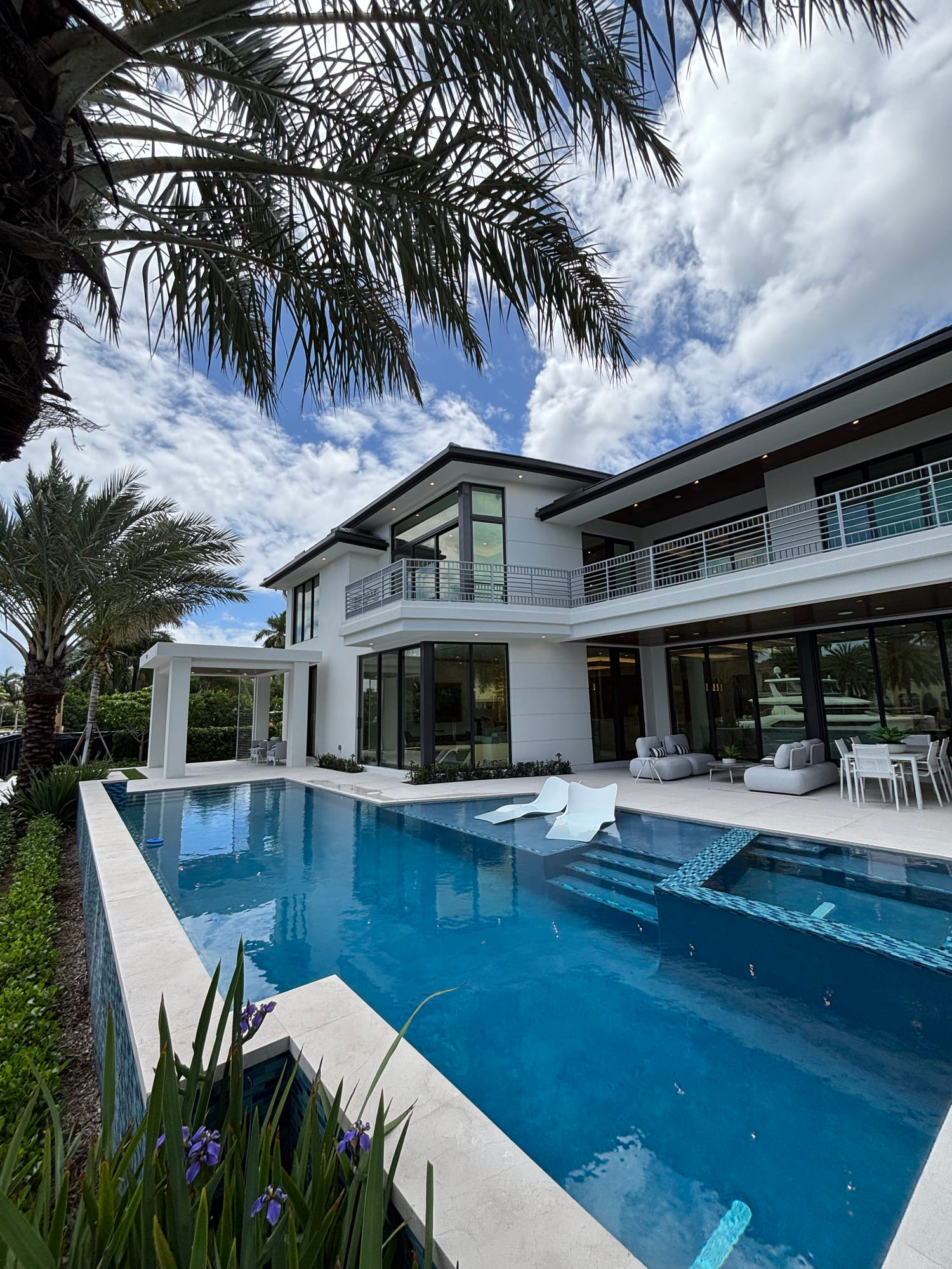 Pool and terrace of a waterfront home looking out toward a canal